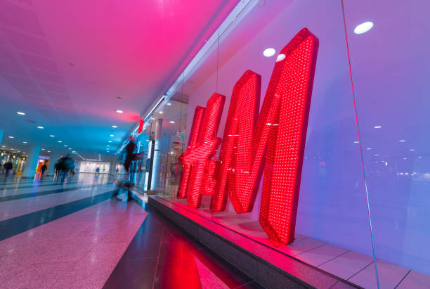HM  H and H H&amp;M sign and motion blurred shopper Stockholm, Sweden - February 15, 2018: Motion blurred shopper passing H+M sign. The sign is one of the new LED signs. A scene from central Stockholm, home of H+M, Hennes och Mauritz. h and m stock pictures, royalty-free photos & images