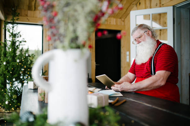 istock Santa Claus at his living room using digital tablet 929997226