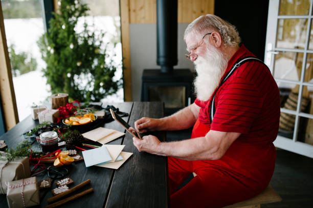 babbo natale usa il tablet digitale nella sua capanna di tronchi - scandinavian men glasses shirt foto e immagini stock