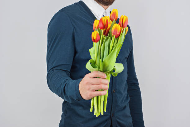 istock Man with a beard holding bouquet of tulips 929998238