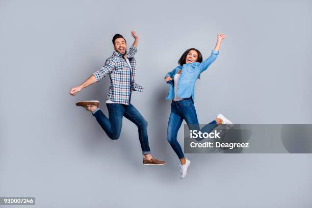 He Vs She Full Length Portrait Of Attractive Playful Cheerful Comic Couple In Casual Outfit Jeans Shirts Jumping Over Grey Background Stock Photo - Download Image Now