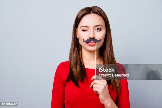 Portrait With Empty Copy Space For Text Of Cool Pretty Charming Crazy Girl Holding Black Paper Party Mustache On Stick Winking With Pout Lips Standing Over Gray Background Stock Photo - Download Image Now