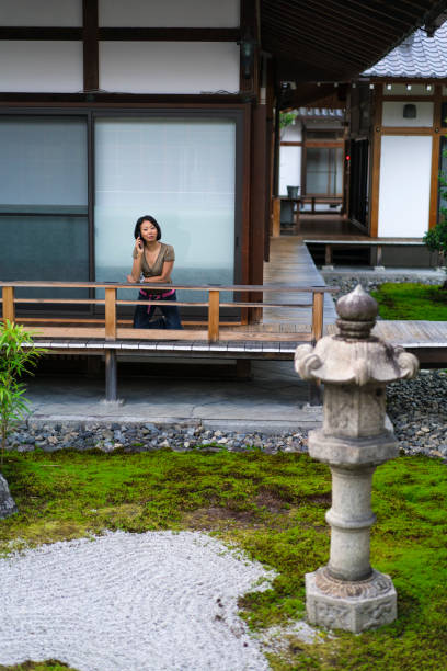 vue de femme, parler au téléphone mobile dans le zen jardin de chion-ji à kyoto, japon - zen like women temple meditating photos et images de collection