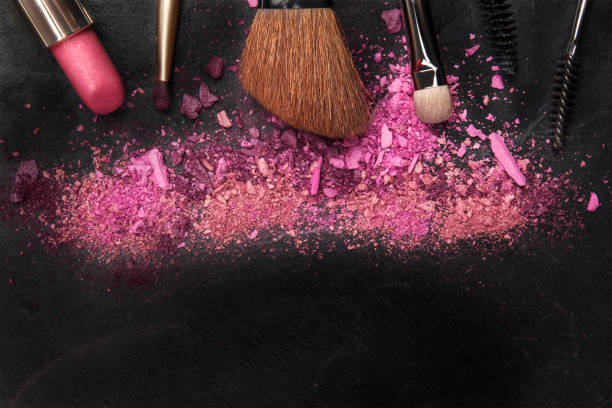 istock Closeup of makeup brushes with eye shadow and lipstick on black with copy space 930022892