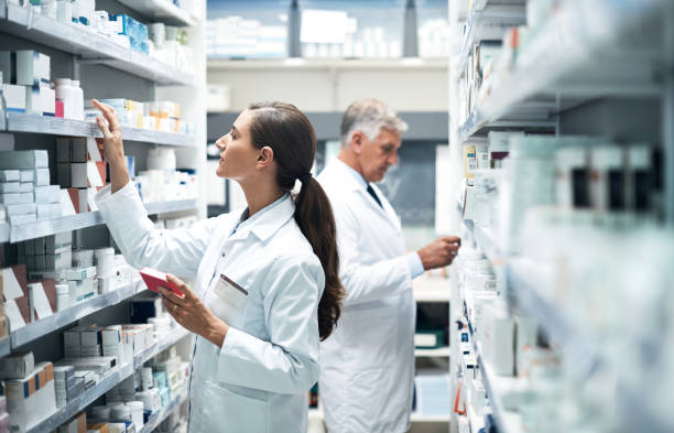 Scouting the shelves for the perfect product Cropped shot of two pharmacists checking products while working together in a dispensary chemist stock pictures, royalty-free photos & images