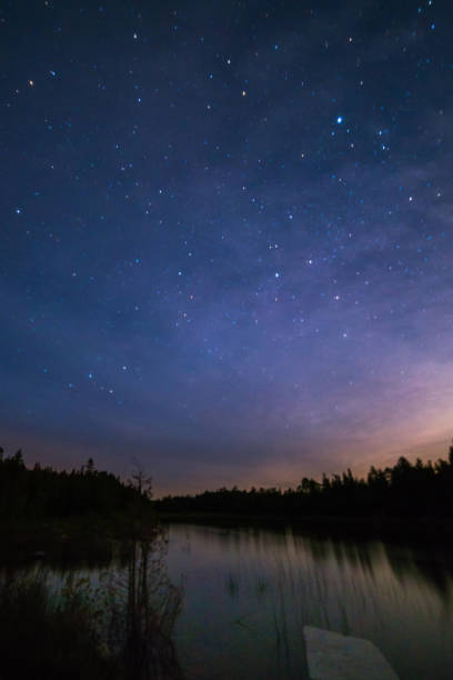 Colorful moonrise over a still river at night with milky way, stars and night sky Small lake reflecting with stars and milky way  at night near Lake Huron, Bruce Peninsula, Ontario northern ontario stock pictures, royalty-free photos & images