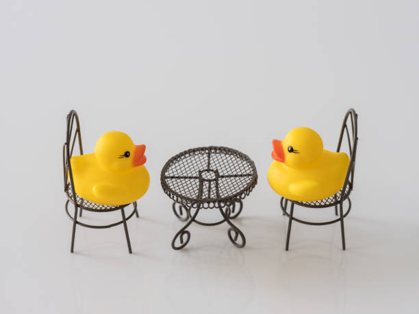 istock Two yellow rubber ducks facing and talking to each other whilst sitting at a table. 930034466