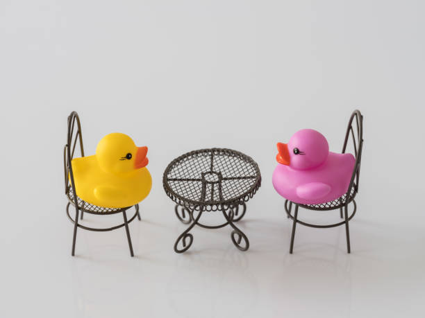 istock Two rubber ducks, one yellow, one purple, facing and talking to each other whilst sitting at a table. 930034470