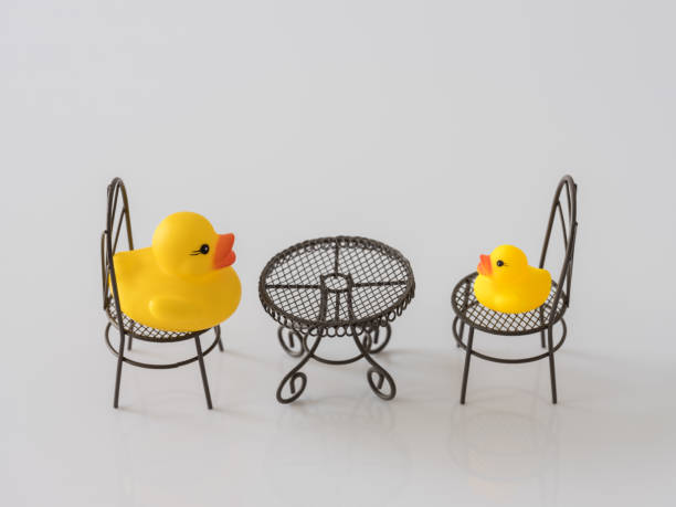 istock Two yellow rubber ducks facing and talking to each other whilst sitting at a table, one big and one small. 930034482