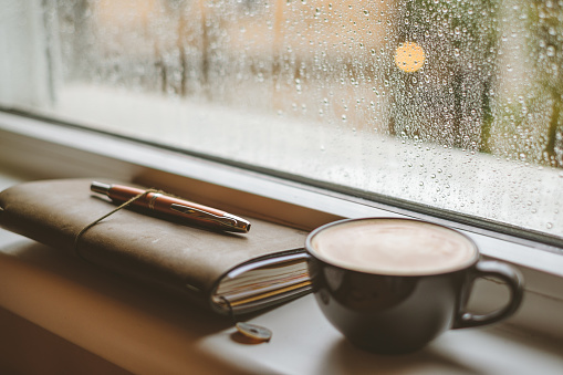 Coffee on a window sill in a rainy day.