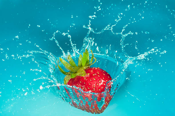 A studio shot of a strawberry splashing into water.