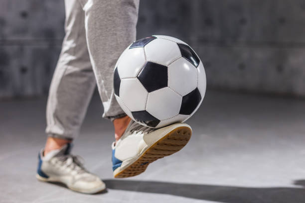 Man holds a soccer ball on his leg
