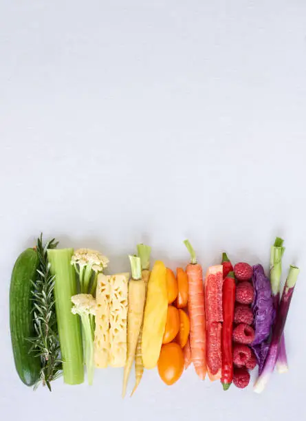 Photo of Flat lay of rainbow spectrum gradient of healthy fruit and vegetables on white background