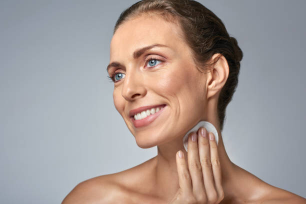 istock Smiling middle aged woman cleaning her neck with cotton wool 930072124