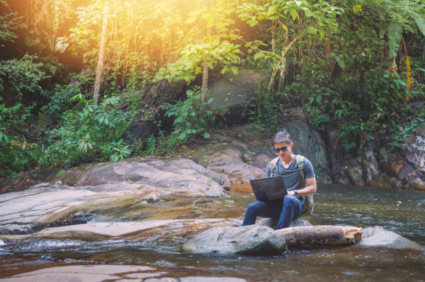istock Hiker backpack travel and online working with his phone at  waterfall  the forest. 930075732