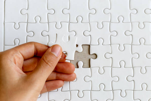 Woman's hand placing put the last white jigsaw puzzle piece to complete the mission, business success concept Woman's hand placing put the last white jigsaw puzzle piece to complete the mission, business success concept final round stock pictures, royalty-free photos & images