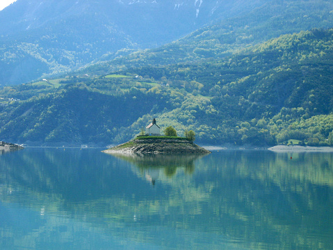 Artificial lake located in the south of the French Alps on the border of the departments of Hautes-Alpes and Alpes-de-Haute-Provence. view of the old church of Savines.