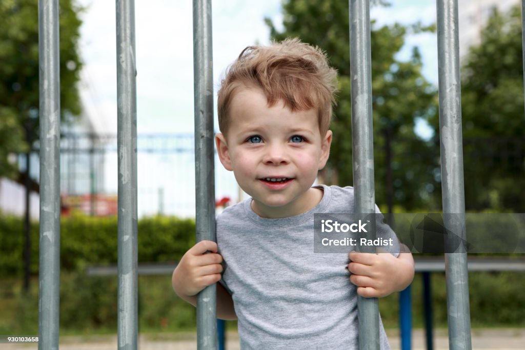 Smiling boy on fence background Smiling boy in park on fence background Beauty Stock Photo