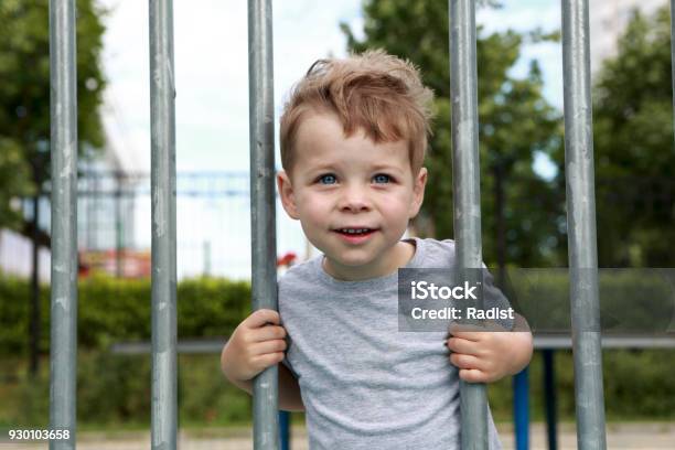 Smiling Boy On Fence Background Stock Photo - Download Image Now - Beauty, Boys, Casual Clothing