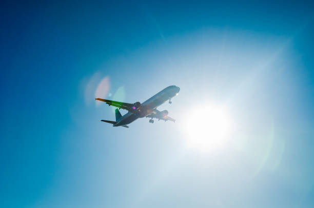 istock Silhouette of airplane flying against bright sun 930110286