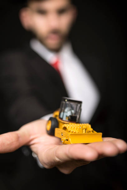 istock Businessman holding bulldozer toy 930115096