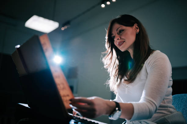 Image of a female pianist turning the sheet music while playing.