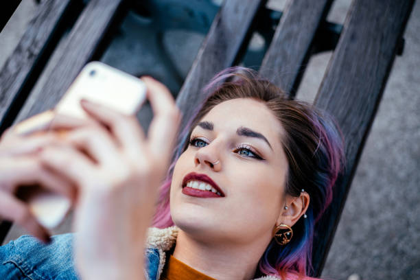 istock Close-up image of a urban girl lying on a bench, using phone. 930115738