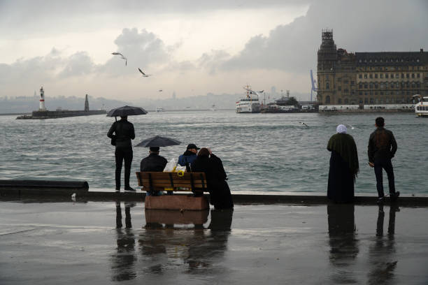 Rainy day at The Istanbul Kadikoy Istanbul, Turkey - March 8, 2018 : Rainy day at The Istanbul, Kadikoy seaside. Some people are watching The Istanbul Landscape with The Haydarpasa Train Station Building and jetty with lighthouse. haydarpaşa stock pictures, royalty-free photos & images
