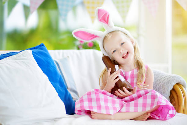 istock Cute little girl wearing bunny ears eating chocolate Easter rabbit 930148728