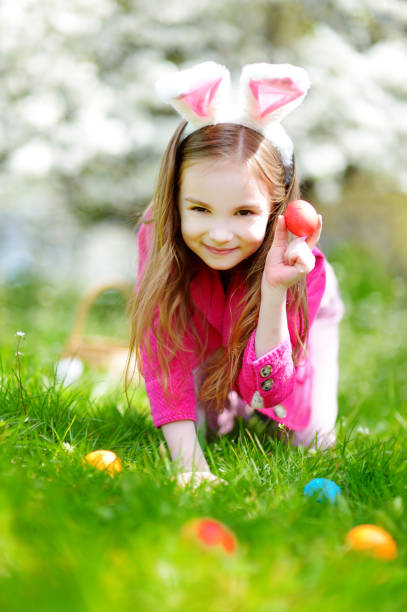 istock Adorable little girl hunting for easter egg in blooming spring garden 930149004