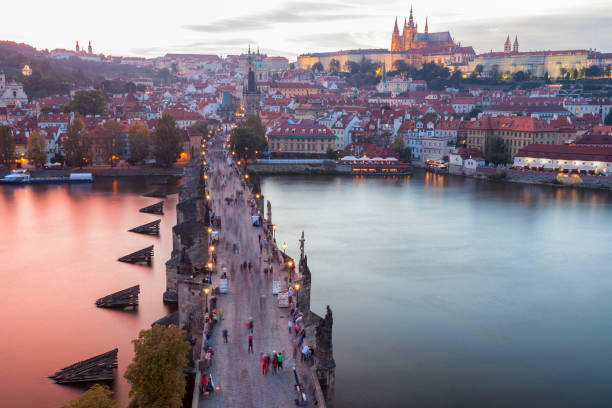 A famous Charles Bridge with crowd of tourists at sunset, River Vltava and Hradcany Castle district, Prague, Czech Republic, elevated view.