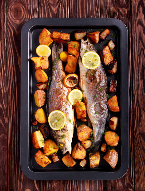 istock Baked sea bass fish and vegetables on black tin 930156128