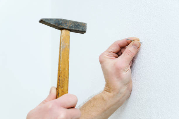 Man's hand  is putting a nail. Man's hand is putting a nail into the wall to hang a picture. hammer photos stock pictures, royalty-free photos & images