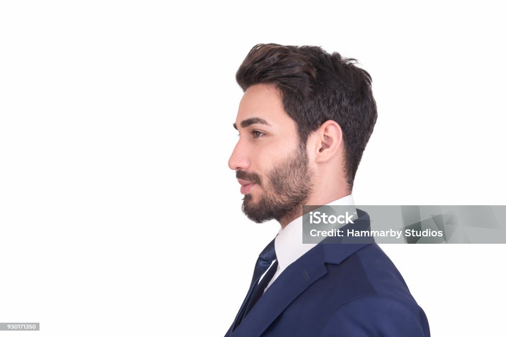 Profile view of young businessman in navy blue suit looking away over white background Profile view of young businessman in suit looking away over white background. There is smiling facial expression on his face. Side view, studio shot. Horizontal composition. Studio shot. Image taken with Nikon D800 and developed from Raw format. Profile View Stock Photo