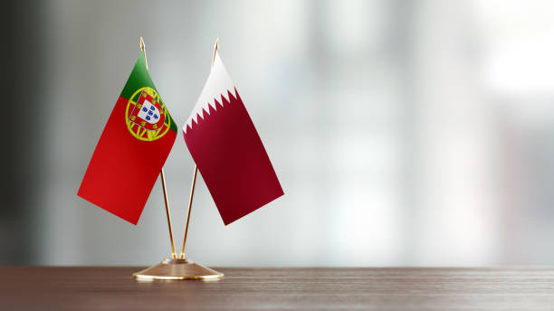 istock Qatari And Portuguese Flag Pair On A Desk Over Defocused Background 930176500