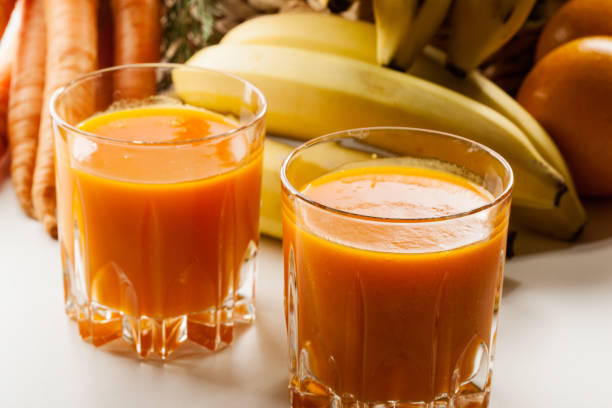 Glass of fruit juice with orange, carrots and banana stock photo