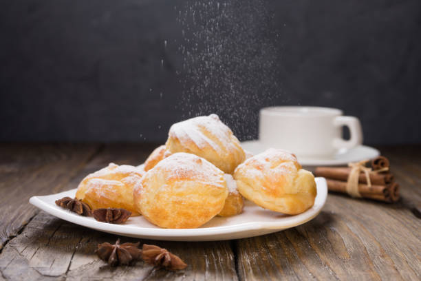 istock Delicious eclairs sprinkled with icing sugar, stand on a wooden table. Copy spase. 930197220