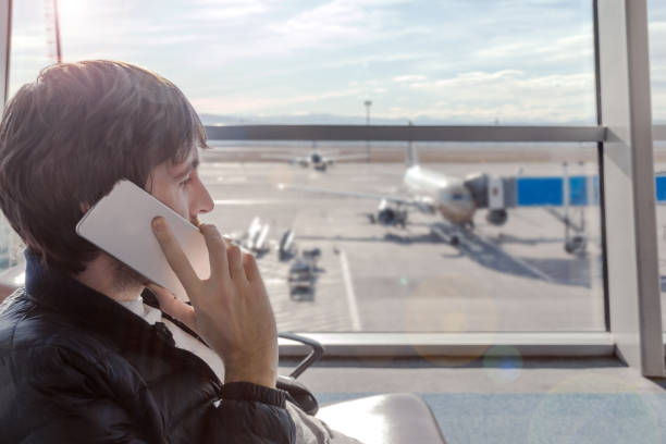 istock Young man talking by mobile phone in airport hall while hi is waiting for boarding plane. 930198290