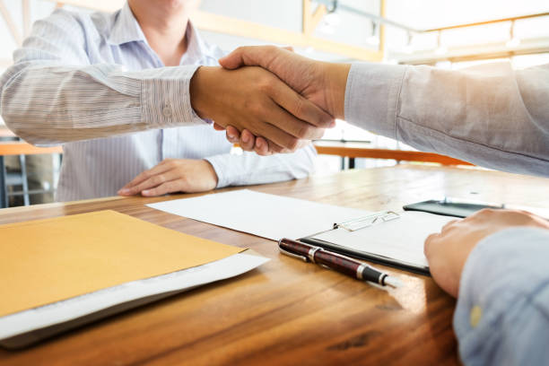 istock Colleagues Shaking Hands Over Desk At Office 930213482
