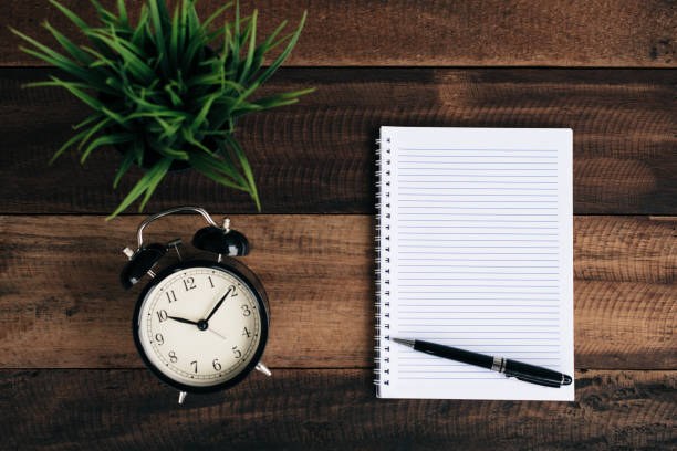 istock Close-Up Of Alarm Clock With Diary On Table 930256268