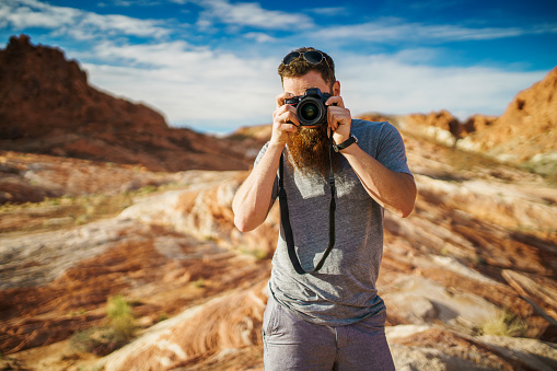 bearded photographer with DSLR camera at valley of fire park in nevada