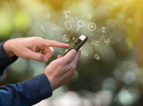 Close up of hands using mobile phone, with technology icons