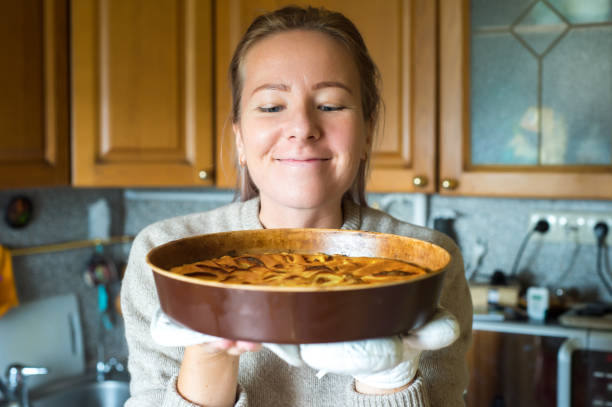 istock Young woman holding a baking tray with a ready cake 930265170