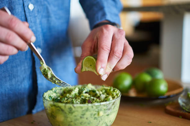adding lime juice to guacamole stock photo