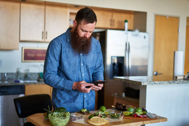 istock making tacos at home in kitchen and using smartphone for recipe 930273812