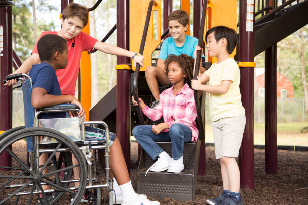 wieloetniczna grupa uczniów na szkolnym placu zabaw, jeden wózek inwalidzki. - child jungle gym playground laughing zdjęcia i obrazy z banku zdjęć