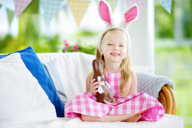 istock Cute little girl wearing bunny ears eating chocolate Easter rabbit 930305574