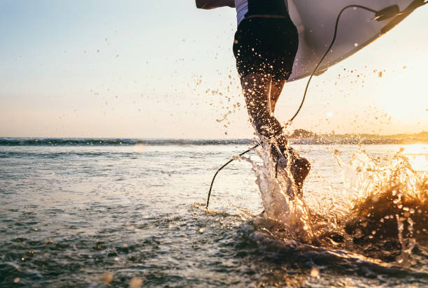 istock Closeup image water splashes from surfer's legs run in ocean with surfboard 930309130
