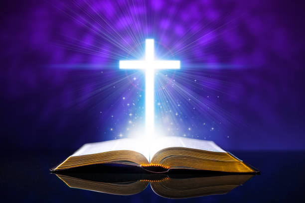 istock Open bible on a glass desk with a glowing cross 930315188