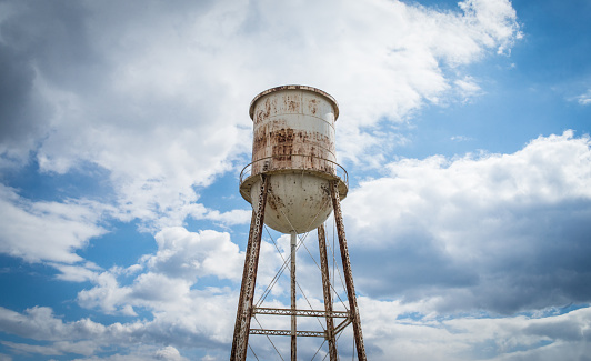 A weathered water tower set against a cloudy blue sky.\n\nTaken near Belmont, North Carolina, USA.